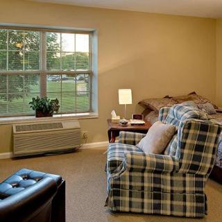 A cozy living room with a plaid armchair and a large window letting in natural light.
