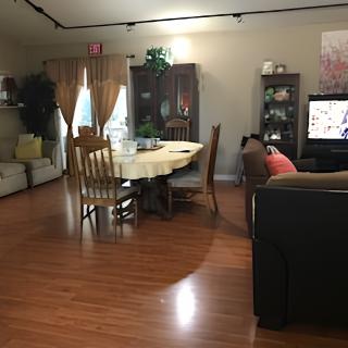 A cozy dining and living area with a wooden table and chairs, adjacent to a seating space with a television.