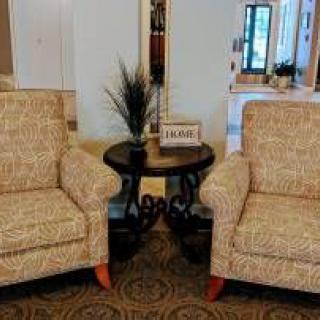 A cozy seating arrangement with two armchairs flanking a small round table in a warmly decorated room.