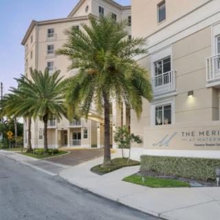 A view of a residential building with palm trees lining the street.