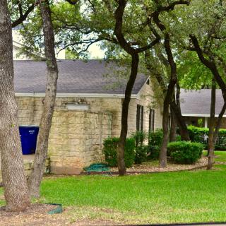 A stone house surrounded by trees and a lush green yard.