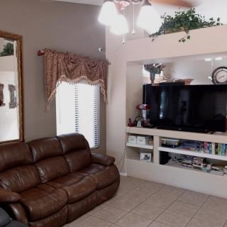 A cozy living room with a brown leather sofa and built-in shelving that houses a television and decorative items.