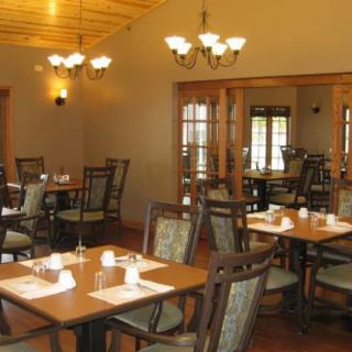 A cozy restaurant interior with neatly arranged tables and chairs, illuminated by warm lighting.