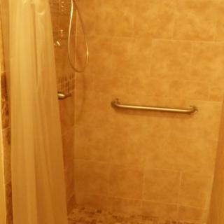 A tiled shower area with a curtain and a grab bar.
