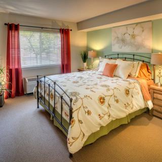 A cozy bedroom with a neatly made bed, soft lighting, and colorful decor.