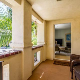 A cozy patio area with tropical plants and comfortable seating leading into a living room.
