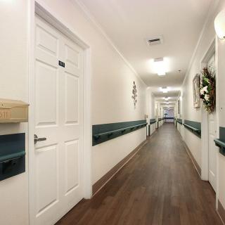 A long, well-lit hallway with wooden flooring and decorated walls.