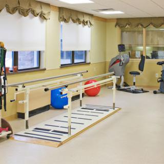 A well-equipped therapy room designed for physical rehabilitation with walking bars and exercise equipment.