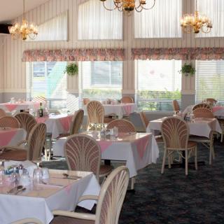 Elegant restaurant dining area with well-set tables and chandeliers.