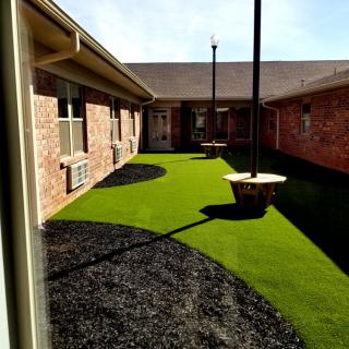 A courtyard with artificial grass and brick walls.