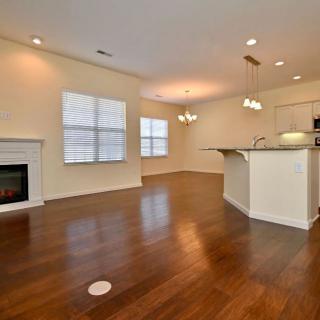 An open-concept living area featuring hardwood floors, a cozy fireplace, and a modern kitchen with an island.