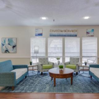 A cozy living room with sofas, chairs, a coffee table, and large windows letting in natural light.