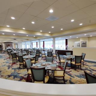 A spacious and well-lit dining area in a modern restaurant, featuring neatly arranged tables and chairs.