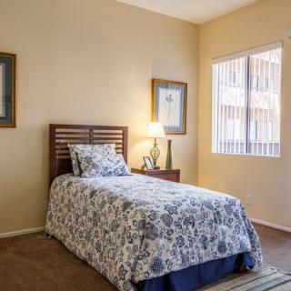 A cozy bedroom with a single bed and natural lighting from a window.