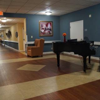 A serene hallway featuring a grand piano and comfortable seating, adorned with artwork.