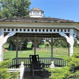 A charming white gazebo in a lush garden setting under a clear blue sky.