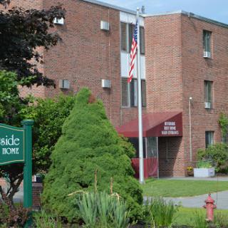 A residential building featuring greenery and an American flag at its entrance.