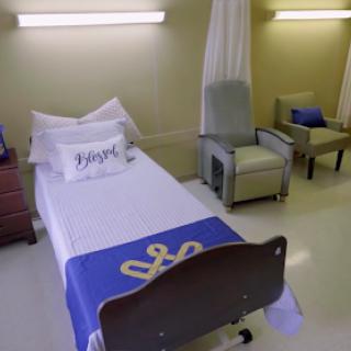 A well-maintained hospital patient room featuring a bed with comfortable bedding and seating.