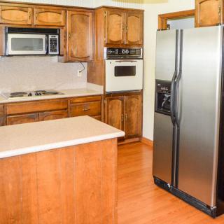 A kitchen featuring wood cabinetry, a stainless steel refrigerator, and built-in appliances.