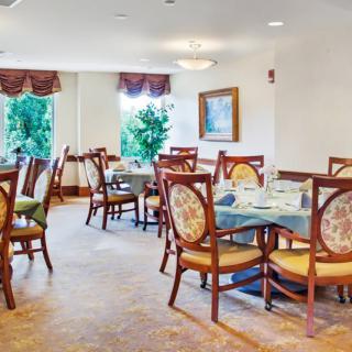 A cozy dining room with elegantly set tables and chairs near large windows.