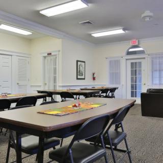 A spacious meeting room with multiple conference tables and chairs set up for a gathering.