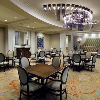An elegant dining area with neatly arranged tables and chairs, featuring a luxurious chandelier overhead.
