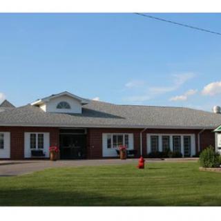 A well-maintained residential building with a green lawn and clear blue sky.
