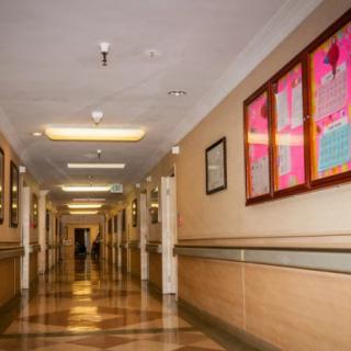 A quiet hospital corridor with bright lights and posters on the wall.
