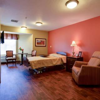 A cozy bedroom with a single bed, armchair, and warm ambient lighting.