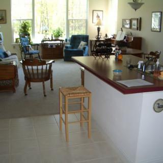 A cozy living area with a kitchen counter and natural light streaming through large windows.