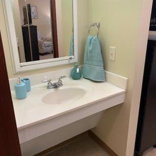 A clean and organized bathroom sink area with a mirror, towel, and soap dispenser.