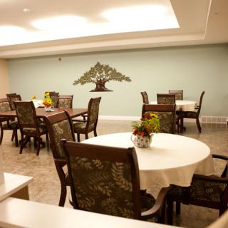A cozy indoor dining room with tables and chairs, featuring wall art on a pastel-colored wall.