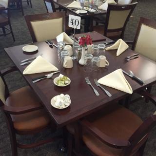 A neatly set dining table with napkins, cutlery, and water glasses in a restaurant.