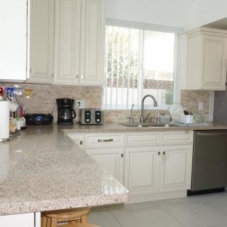 A modern kitchen with white cabinets and granite countertops.