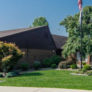 A well-maintained building surrounded by lush greenery and featuring a flagpole.