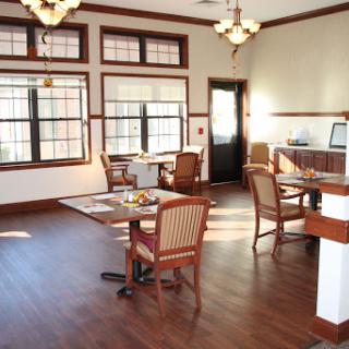 A well-lit dining area featuring wooden flooring and elegant furniture.