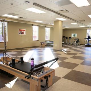 A spacious and well-lit fitness studio equipped with a pilates reformer.