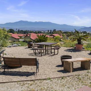 A scenic outdoor seating area with benches and tables overlooking a mountain range.