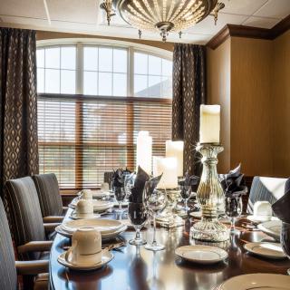 An elegantly set dining table with candles and fine dinnerware in a well-decorated room.