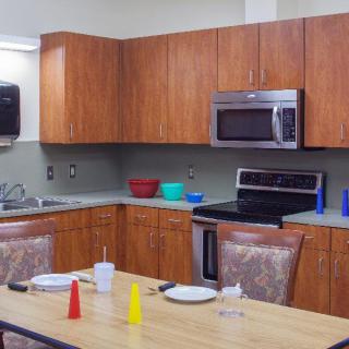 A kitchen setup with a dining table, wooden cabinets, modern appliances, and various dining accessories.