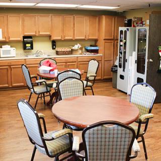 A cozy break room with tables, chairs, a vending machine, and kitchen amenities.