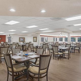 An empty restaurant dining room with neatly arranged tables and chairs under bright lighting.