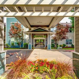 A modern building entrance with a covered walkway and vibrant landscaping.
