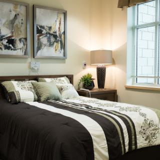 A modern and stylish bedroom featuring elegant bedding, decorative pillows, and artwork that enhances the ambiance.