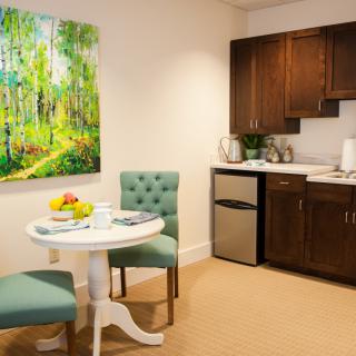 A cozy kitchenette with a small round table, two chairs, and a painting on the wall.