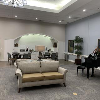 A spacious and elegantly designed lobby featuring a comfortable sofa, grand piano, and modern lighting.