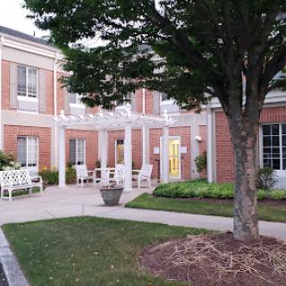 A charming exterior view of a brick building with a landscaped entrance and seating area.