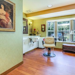 A cozy salon interior with a styling chair, sink, and large window.