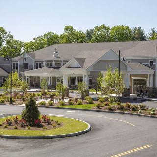 A large residential building with a landscaped driveway and surrounding greenery.