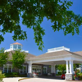 The entrance to a building surrounded by trees under a clear blue sky.